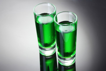 Two glasses of absinthe on grey background