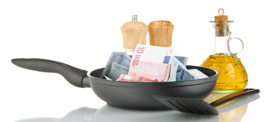Banknotes in a frying pan with cooking spatula isolated on