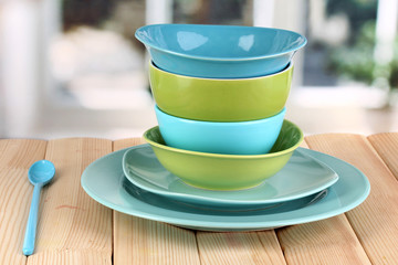 Blue and green tableware on wooden table on window background