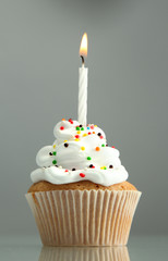 tasty birthday cupcake with candle, on grey background