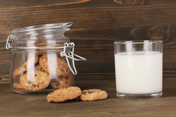 Glass of milk with cookies on wooden table close-up