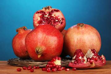 Ripe pomegranates on wicker cradle on blue background