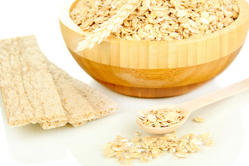 wooden bowl full of oat flakes with wooden spoon, spikelets and