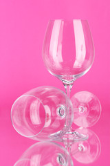 Two empty wine glasses on color background