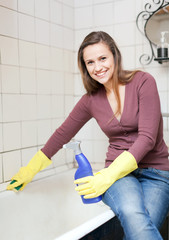 Smiling girl cleans bathtub in bathroom