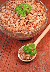 Buckwheat porridge with parsley in glass bowl, close-up
