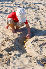 Kid playing on the beach with balls in a sunny day.