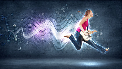 young woman playing on electro guitar and jumping