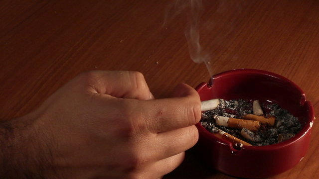 Detail of Male hand smoking Cigarette in ashtray