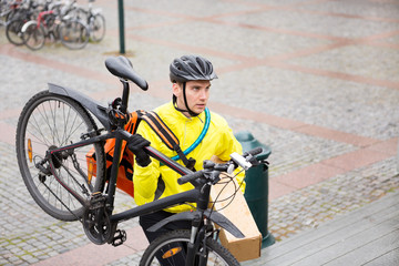 Naklejka premium Courier Delivery Man With Package And Bicycle Walking Up Steps