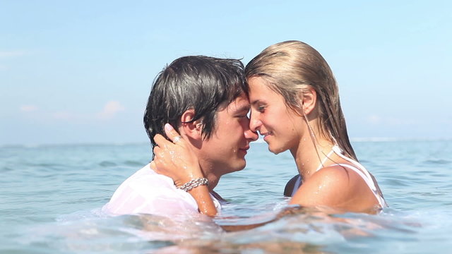 Pretty woman swimming in ocean then kissing her boyfriend