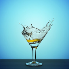 martini glass with lemon splashing on a blue background