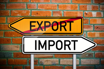 Wegweiser vor Ziegelsteinwand mit Export und Import