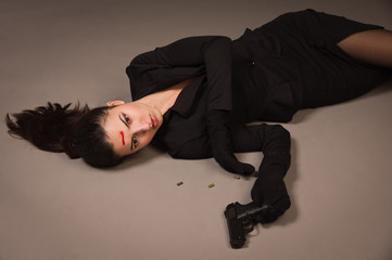Woman in a black suit with gun lying on the floor