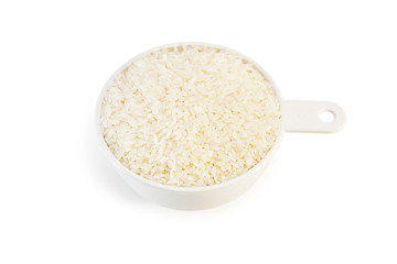 Measuring cup of rice on white