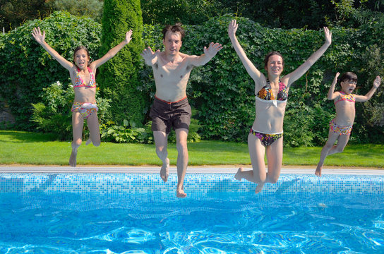 Happy family jumping to swimming pool, fun on summer vacation