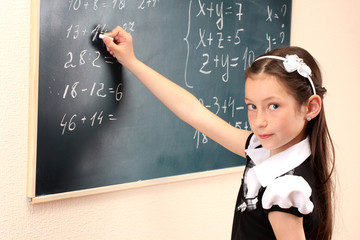 beautiful little girl writing on classroom board