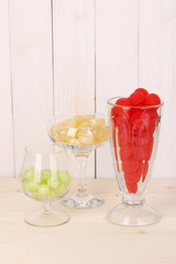 Color candies in glasses on wooden background