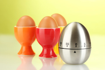 egg timer and egg in color stand on green background