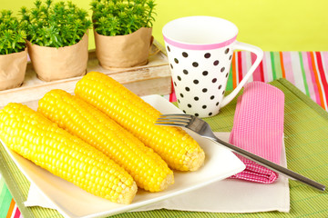 boiled corn and a cup on a green background