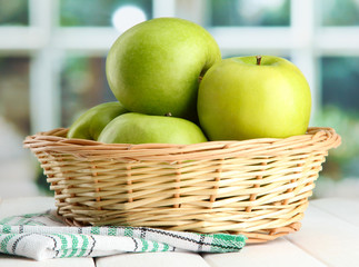 Ripe green apples with leaves in basket,