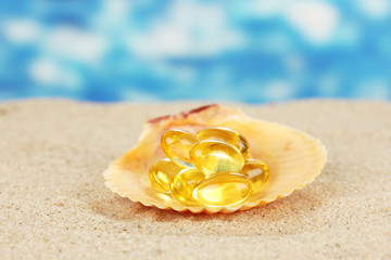 fish oil in the shell in the sand on a blue background