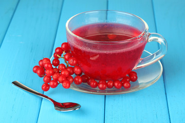 glass cup with broth viburnum on blue wooden background