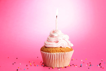 tasty birthday cupcake with candle, on pink background