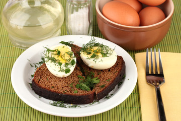 Boiled eggs  on dark bread on green background