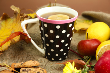 cup of hot tea and autumn leaves, on burlap background