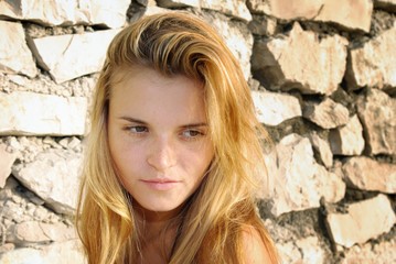 Portrait of attractive young woman posing in front of stone wall