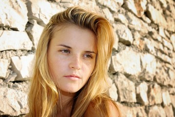 Portrait of attractive young woman posing in front of stone wall