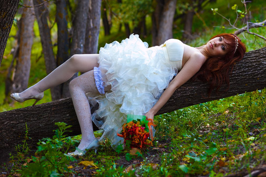 Bride red haired woman in a white dress with sexy legs with gart