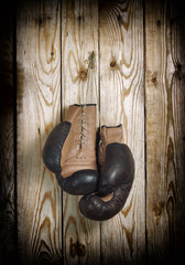 Brown old boxing gloves with a lace over old wooden wall - 47053306