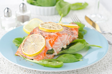 Baked salmon fillet with lemon and spinach on a plate