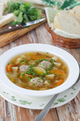 Plate of vegetable soup with meatballs on the wooden table verti