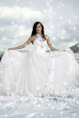 Fototapeta na wymiar pretty young woman posing in wedding dress on winter snow
