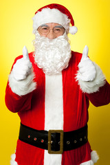Cheerful male in Santa costume showing double thumbs up