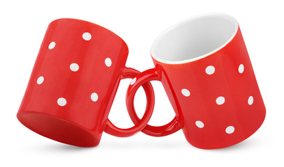 Two coupled red polka dot mugs on white with clipping path