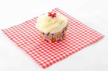 one cupcake buttercream on a red patterned napkin and flower