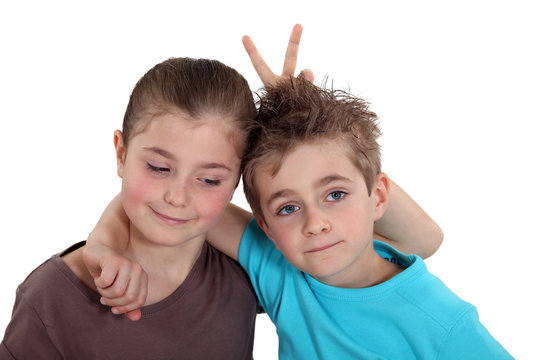 Girl making a peace sign over her friend's head