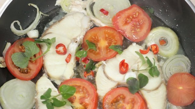 fish fillet fried with fresh herbs in a pan