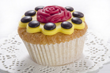 Cupcake mit gelbem Zuckerguss und roter Rose
