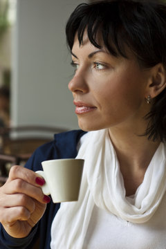 Closeup of a cute woman looking away with cup coffe