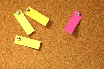 Post-it notes pushpins on cork board.