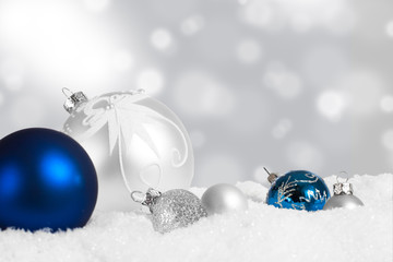 Silver and blue Christmas ornaments in snow