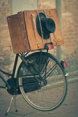 Black hat and brown suitcase on old bike