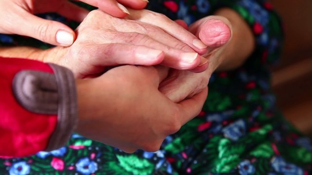 Yung hand comforting a pair of old wrinkled hands