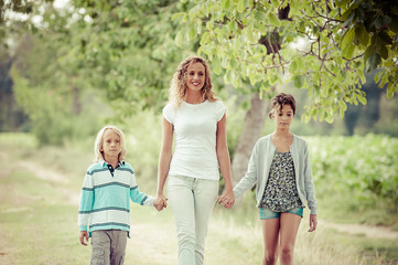 Fototapeta premium Beautiful Young Woman with Two Children Outside