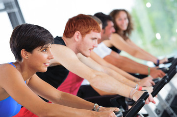 Group of five people in the gym, exercising their legs doing car
